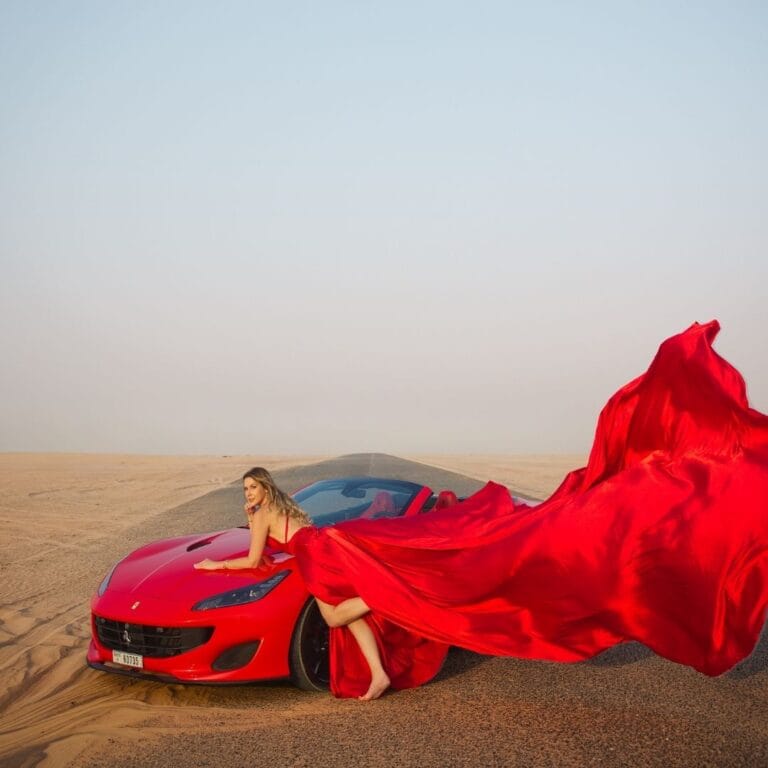 Red flying dress photoshoot in Dubai desert with luxury car and premium professional photography experience