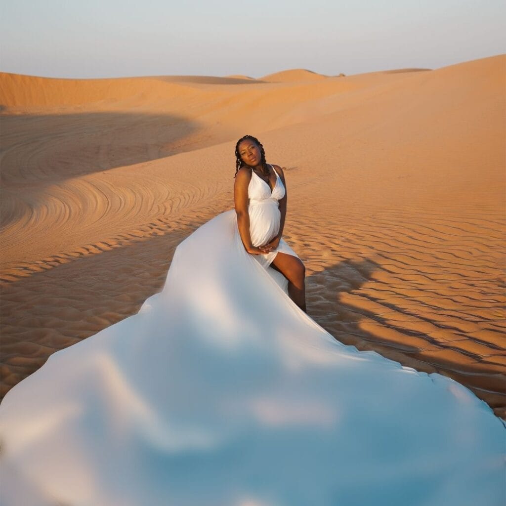 Maternity flying dress photoshoot in Dubai desert with white flowing dress and luxury professional photography experience