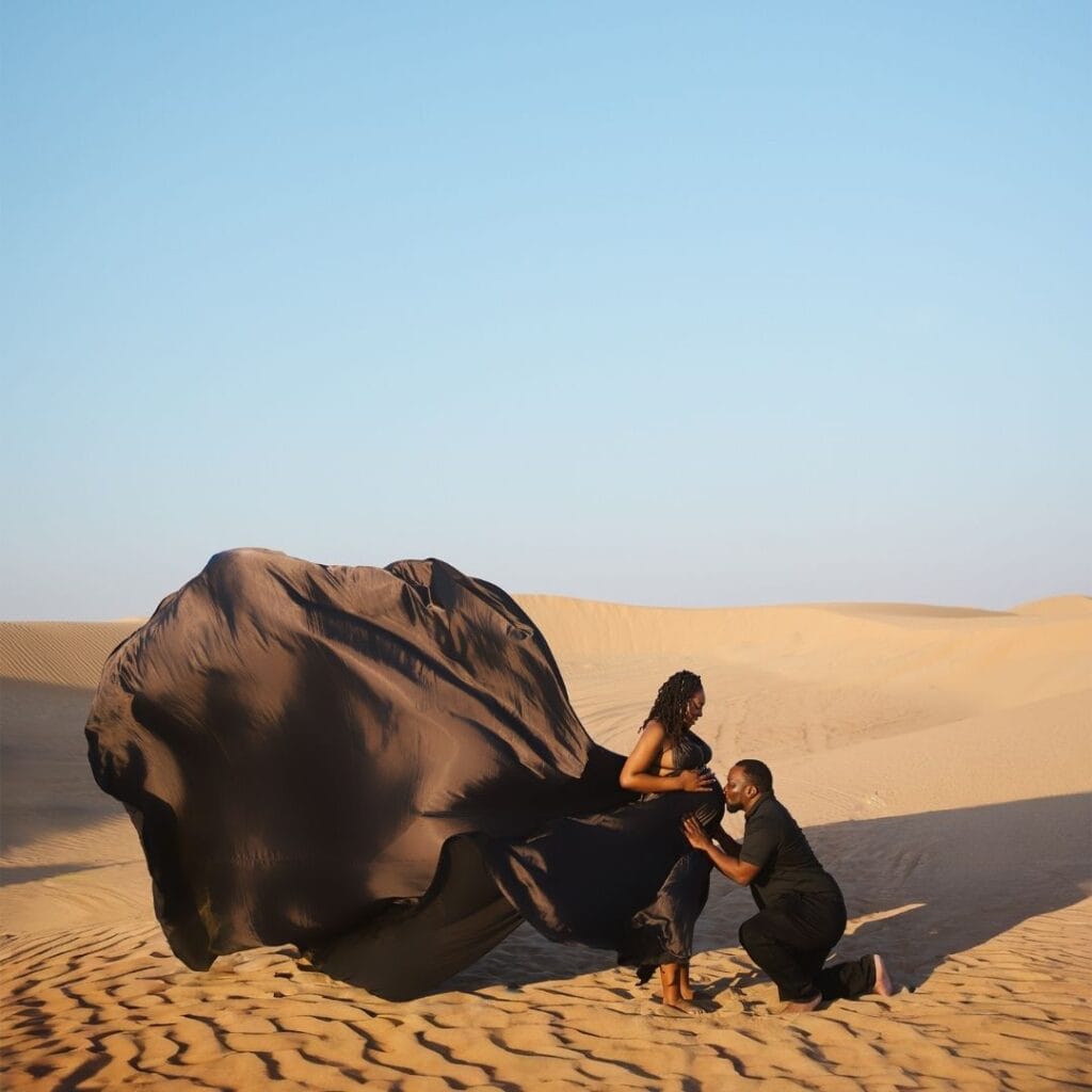 Maternity flying dress photoshoot in Dubai desert with black flowing dress and luxury professional photography experience