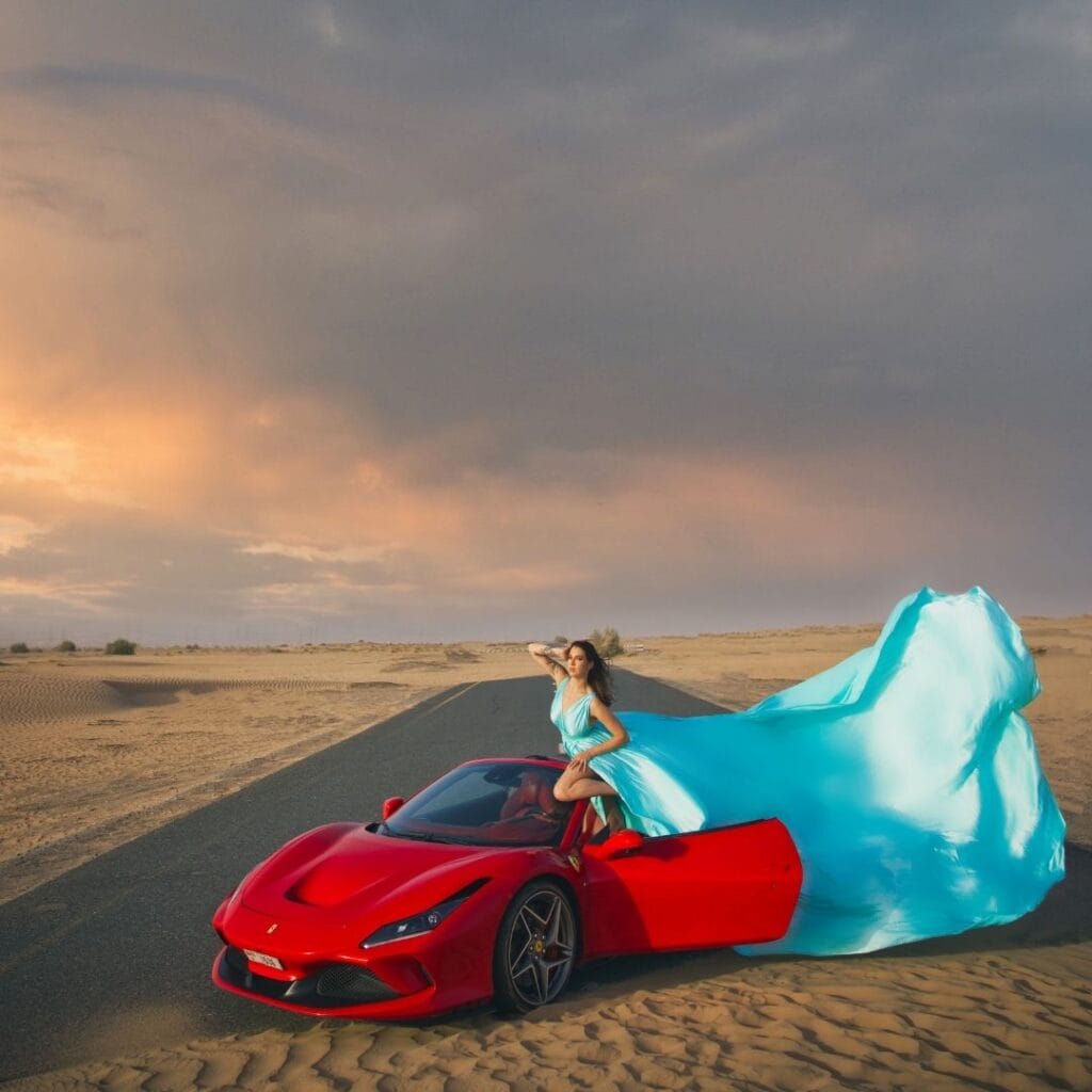 Turquoise flying dress photoshoot in Dubai desert with luxury car and premium professional photography experience