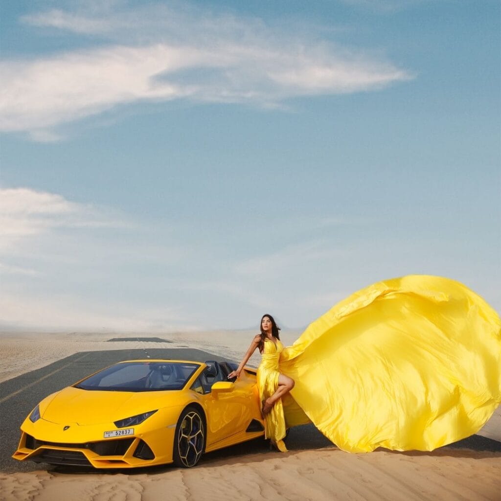 Yellow flying dress photoshoot in Dubai desert with luxury car and premium professional photography experience